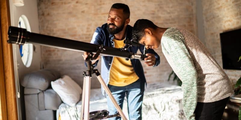 father and son looking through refractor telescope