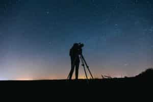 man with telescope on starry night