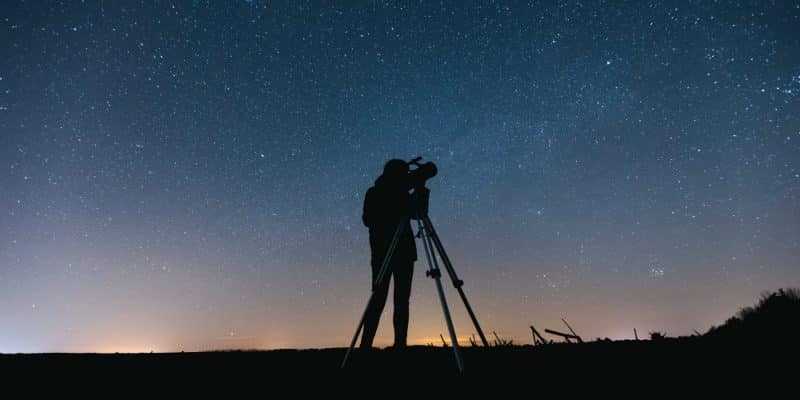 man with telescope on starry night