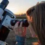 young woman looking through a telescope eyepiece