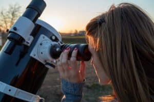 young woman looking through a telescope eyepiece