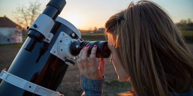 young woman looking through a telescope eyepiece