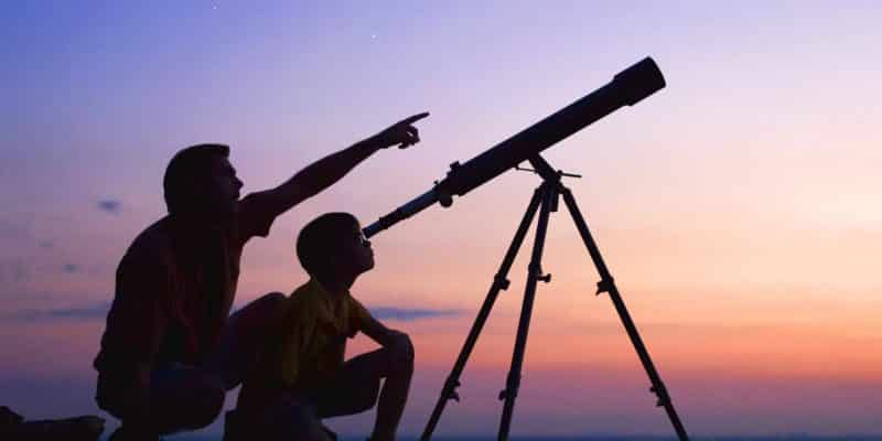 boy and father looking through a telescope