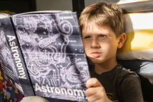 boy reading book about astronomy