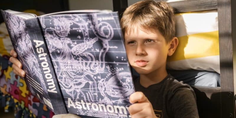 boy reading book about astronomy