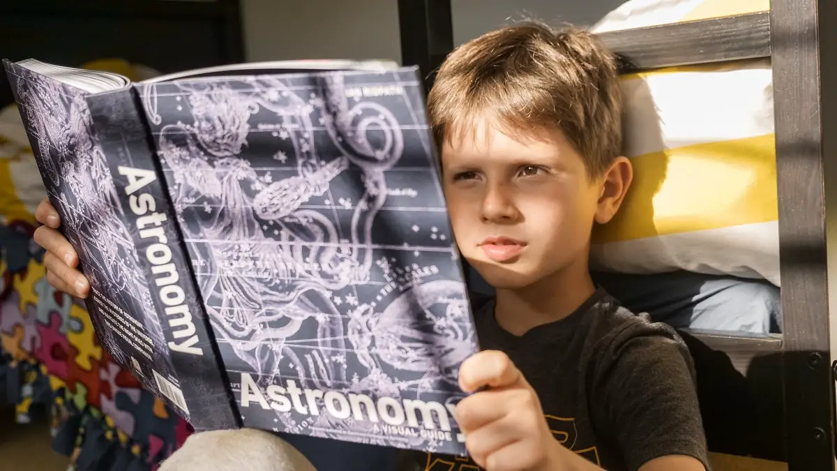 boy reading book about astronomy